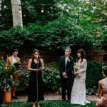 Bride and groom look on as family member does a reading Philadelphia garden wedding