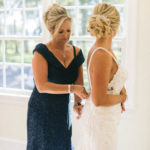 mother helps bride with her wedding gown